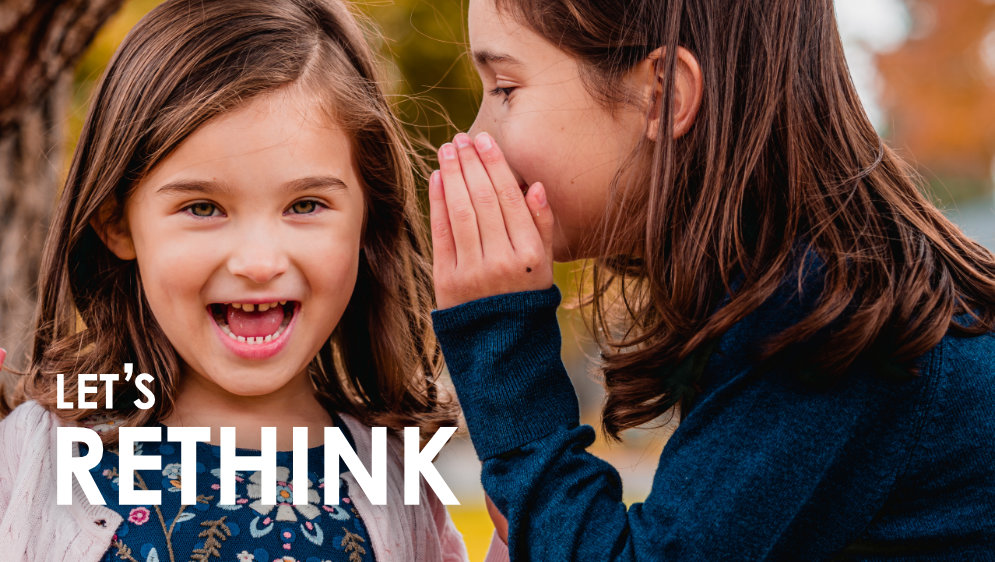 One girl whispering in the ear of another girl